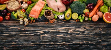 Sağlıklı gıda arka plan. Sağlıklı gıda, tavuk fileto, çiğ et, balık, avokado, brokoli, taze sebze, fındık ve meyve kavramı. Ahşap bir arka plan üzerinde. Üstten Görünüm. Kopya alanı.