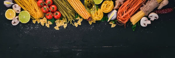 Bir makarna, erişte, makarna, tagliatelle, fettuccine, dizi Farfalle. İtalyan yemek, taze sebze ve baharat. Siyah ahşap arka plan üzerinde. Üstten Görünüm. Kopya alanı.