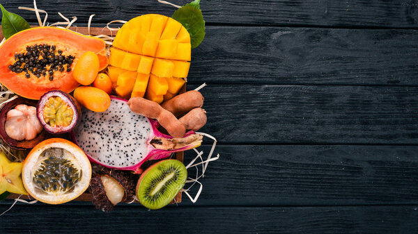 Фруктовый дракон, папайя, маракуя, киви, манго и гранадилья в деревянной коробке. Свежие тропические фрукты. На деревянном фоне. Вид сверху. Копирование пространства
.