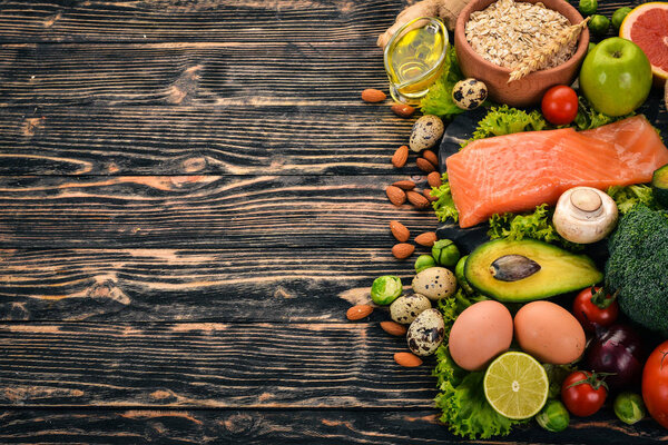 Healthy food. Fish salmon, avocado, broccoli, fresh vegetables, nuts and fruits. On a wooden background. Top view. Copy space.