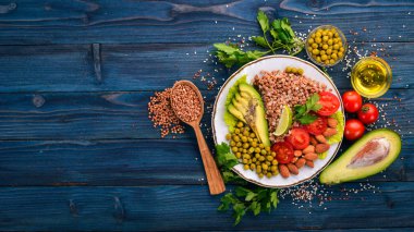 Sağlıklı gıda. Karabuğday, cherry domates, avokado, badem ve yeşil bezelye. Ahşap bir arka plan üzerinde. Üstten Görünüm. Metniniz için boş alan.