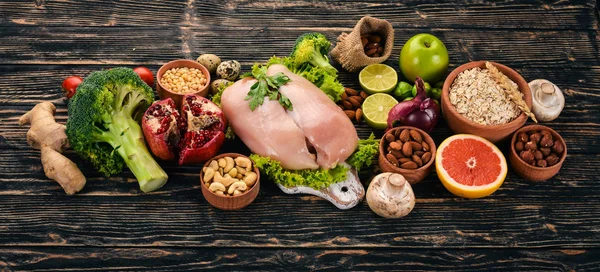 健康食品 鸡肉鱼片 花椰菜 新鲜蔬菜 坚果和水果 在木制背景上 顶部视图 复制空间 — 图库照片