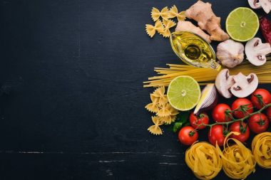 Bir makarna, erişte, makarna, tagliatelle, fettuccine, dizi Farfalle. İtalyan yemek, taze sebze ve baharat. Siyah ahşap arka plan üzerinde. Üstten Görünüm. Kopya alanı.