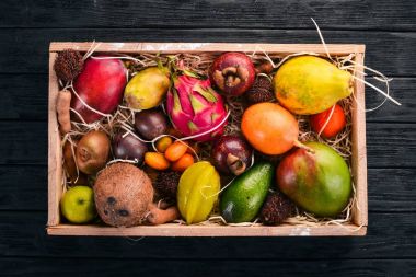Tahta bir kutuda tropik meyve. Papaya, Dragon Fruit, rambutan, tamarind, kaktüs meyvesi, avokado, granadilla, carambola, kumquat, mango, mangosteen, tutku meyvesi, hindistan cevizi.