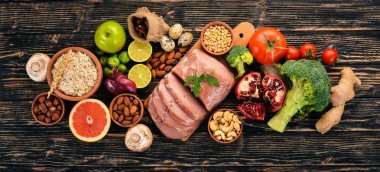 Healthy food. Raw meat, avocado, broccoli, fresh vegetables, nuts and fruits. On a wooden background. Top view. Copy space. clipart