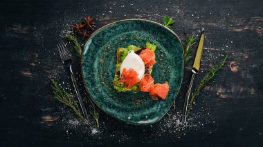 Kahvaltı. Haşlanmış yumurta, tost ekmek üzerinde marul üzerinde somon. Siyah ahşap arka plan üzerinde. Kopya alanı.