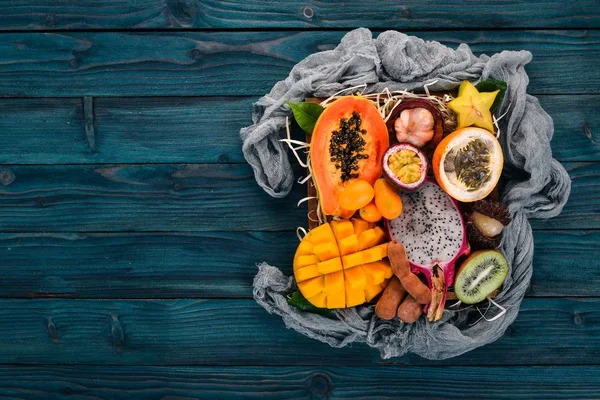 Fruit dragon, papaya, maracuya, kiwi, mango and granadilla in a wooden box. Fresh Tropical Fruits. On a wooden background. Top view. Copy space.