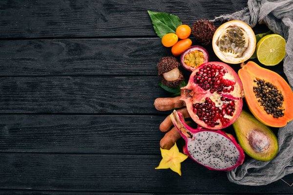 Плоды дракона, папайя, кумкват, гранадилла, авокадо, маракуйя. Тропические фрукты. На деревянном фоне. Вид сверху. Копирование пространства
.