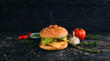 Fasulye domates ve marul ile Burger. Amerikan geleneksel yemekleri. Siyah ahşap arka plan üzerinde. Kopya alanı.