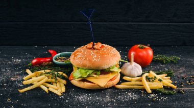 Fasulye domates ve marul ile Burger. Amerikan geleneksel yemekleri. Siyah ahşap arka plan üzerinde. Kopya alanı.