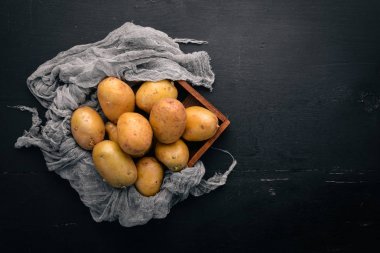 Çiğ patates siyah ahşap zemin. Yemek. Metin için özgür yer. Üstten Görünüm.