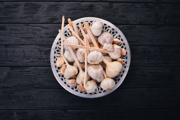 Garlic on a plate. Fresh garlic on a wooden background. Top view. Copy space.