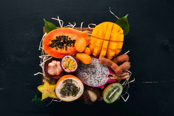 Fruit dragon, papaya, maracuya, kiwi, mango and granadilla in a wooden box. Fresh Tropical Fruits. On a wooden background. Top view. Copy space.