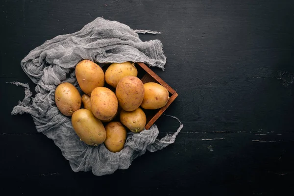 Çiğ patates siyah ahşap zemin. Yemek. Metin için özgür yer. Üstten Görünüm.