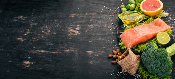 Здоровое питание. Рыбный лосось, авокадо, брокколи, свежие овощи, орехи и фрукты. На черном фоне. Вид сверху. Копирование пространства
.