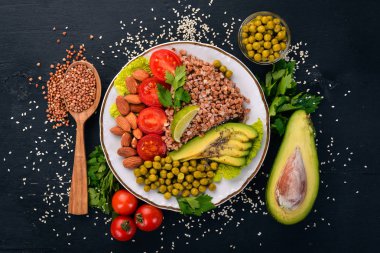 Sağlıklı gıda. Karabuğday, cherry domates, avokado, badem ve yeşil bezelye. Ahşap bir arka plan üzerinde. Üstten Görünüm. Metniniz için boş alan.