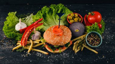 Somon, peynir ve salata ile Burger bırakıyor. Amerikan geleneksel yemekleri. Siyah ahşap arka plan üzerinde. Kopya alanı.