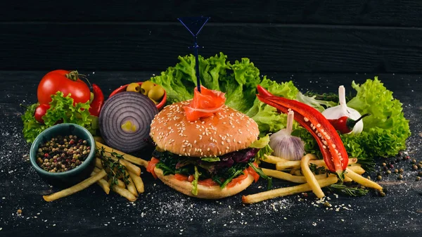 Burger with salmon, cheese and salad leaves. American Traditional Food. On a black wooden background. Copy space.