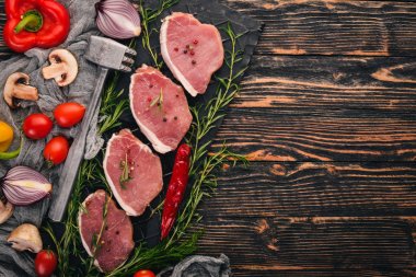 Çiğ et. Biberiye ve baharat siyah ahşap zemin sığır eti biftek. Üstten Görünüm. Metin için boş alan.