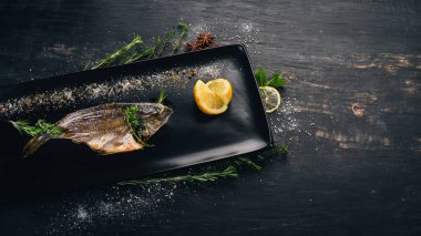 Dorado balık doğranmış domates ve sebze ile. Siyah ahşap arka plan üzerinde. Kopya alanı.