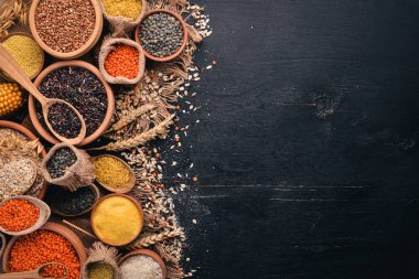 Kabuğu çıkarılmış tane ve tahıl kümesi. Buğday, mercimek, pirinç, darı, arpa, Mısır, siyah pirinç. Siyah bir arka plan üzerinde. Üstten Görünüm. Kopya alanı.