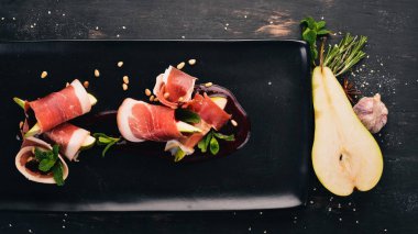 Prosciutto armut ve meyve sosu ile. Soğuk aperatifler. Üstten Görünüm. Siyah ahşap arka plan üzerinde. Kopya alanı.