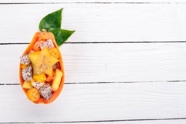 Tropikal meyve salatası servis yarım bir Papaya. Dragon meyve, rambutan, demirhindi, kaktüs meyve, avokado, mango. Ahşap bir arka plan üzerinde. Üstten Görünüm.