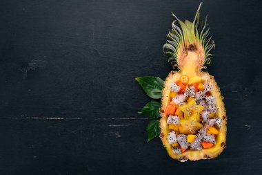 Egzotik meyve salatası yarım bir ananas servis. Papaya, Dragon meyve, demirhindi, kaktüs meyve, mango, mangosteen ahşap arka plan üzerinde. Üstten Görünüm.