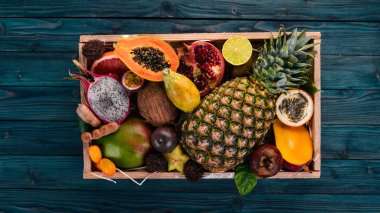Tahta bir kutuda tropik meyve. Papaya, Dragon Fruit, rambutan, tamarind, kaktüs meyvesi, avokado, granadilla, carambola, kumquat, mango, mangosteen, tutku meyvesi, hindistan cevizi.