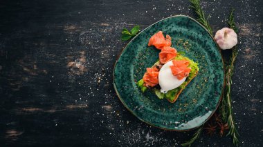 Kahvaltı. Haşlanmış yumurta, tost ekmek üzerinde marul üzerinde somon. Siyah ahşap arka plan üzerinde. Kopya alanı.