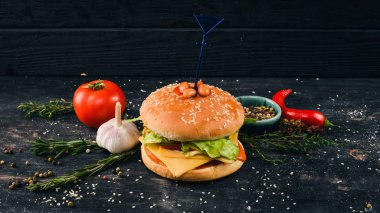 Fasulye domates ve marul ile Burger. Amerikan geleneksel yemekleri. Siyah ahşap arka plan üzerinde. Kopya alanı.