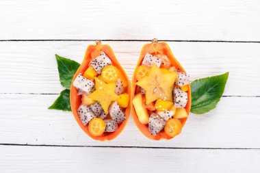 Tropikal meyve salatası servis yarım bir Papaya. Dragon meyve, rambutan, demirhindi, kaktüs meyve, avokado, mango. Ahşap bir arka plan üzerinde. Üstten Görünüm.
