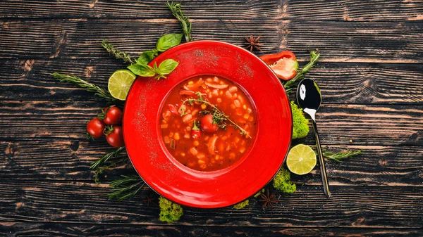 Tomato soup of corn, chicken and chili pepper. Top view. On a black wooden background. Copy space.