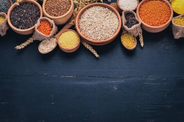 Kabuğu çıkarılmış tane ve tahıl kümesi. Buğday, mercimek, pirinç, darı, arpa, Mısır, siyah pirinç. Siyah bir arka plan üzerinde. Üstten Görünüm. Kopya alanı.
