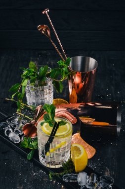 Cin-tonik alkollü kokteyl. Orange, likör, buz. Siyah bir ahşap arka plan üzerinde.