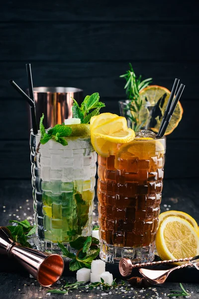 Long Island and Mojito Alcoholic Cocktails. On a black wooden background.