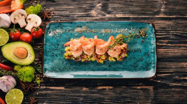 Avokado bir yastık ve taze sebze kaplan karides. Üstten Görünüm. Siyah ahşap arka plan üzerinde. Kopya alanı.