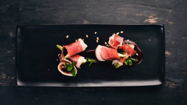 Prosciutto armut ve meyve sosu ile. Soğuk aperatifler. Üstten Görünüm. Siyah ahşap arka plan üzerinde. Kopya alanı.
