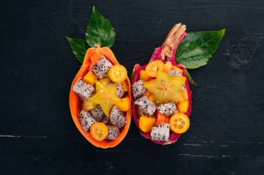 Tropikal meyve salatası servis yarım bir Papaya. Dragon meyve, rambutan, demirhindi, kaktüs meyve, avokado, mango. Ahşap bir arka plan üzerinde. Üstten Görünüm.