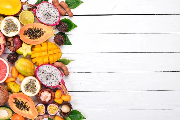 Tropical fruits, papaya, Dragon Fruit, rambutan, tamarind, cactus fruit, avocado, granadilla, carambola, kumquat, mango, mangosteen, passionfruit, coconut. On a wooden background.