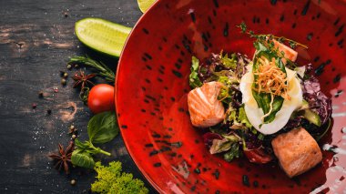 Sezar salatası somon ve haşlanmış yumurta. Üstten Görünüm. Siyah ahşap arka plan üzerinde. Kopya alanı.