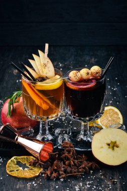 Şarap, tarçın ve elma ile sıcak alkollü kokteyller. Siyah arka plan çubuğunda.