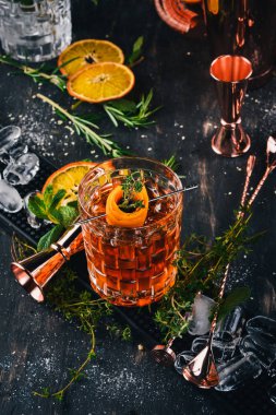 Alkol kokteyl Negroni. Orange, likör, buz. Siyah bir ahşap arka plan üzerinde.