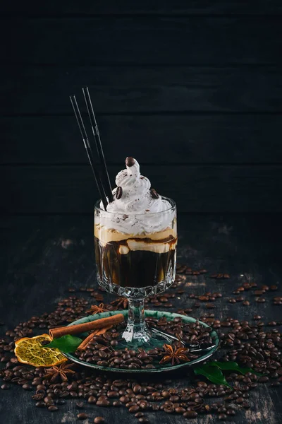 Aromatic cup of coffee with Irish whiskey and cream. On a black wooden background. Top view. Copy space.