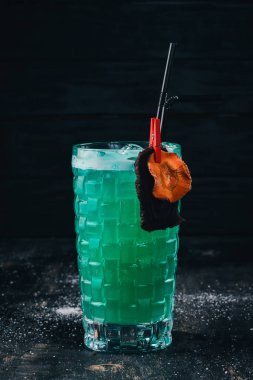 Alkol kokteyl mavi lagün. Orange, likör, buz. Siyah bir ahşap arka plan üzerinde.