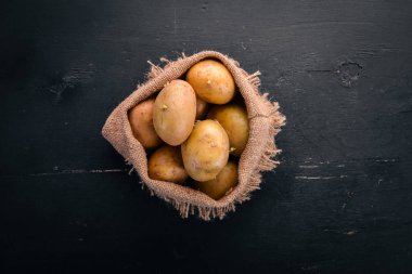 Çiğ patates siyah ahşap zemin. Yemek. Metin için özgür yer. Üstten Görünüm.
