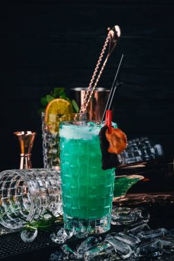Alkol kokteyl mavi lagün. Orange, likör, buz. Siyah bir ahşap arka plan üzerinde.