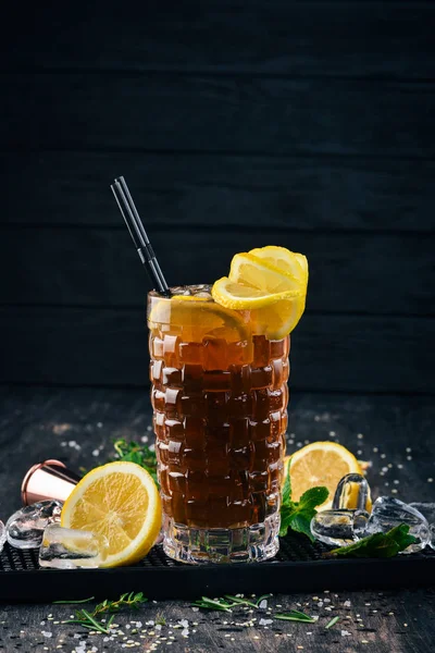 Alcohol cocktail Long Island. On a black wooden background.