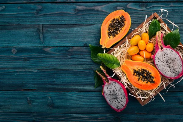 Papaya, Dragon Fruit, Cactus Fruit. Fresh Tropical Fruits. On a wooden background. Top view. Copy space.