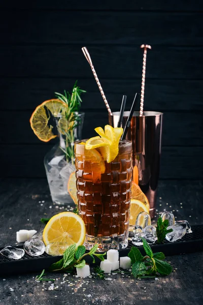 Alcohol cocktail Long Island. On a black wooden background.